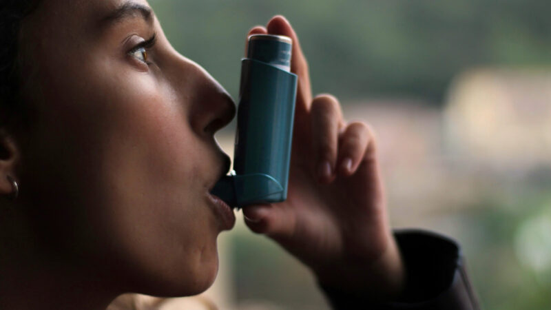 Health and medicine - Young girl using blue asthma inhaler to prevent an asthma attack. Pharmaceutical product to prevent and treat asthma.