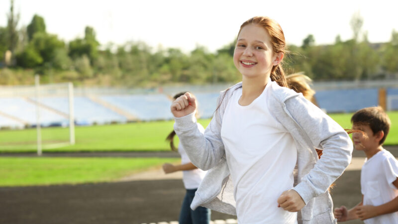 Sporty children running on track at stadium