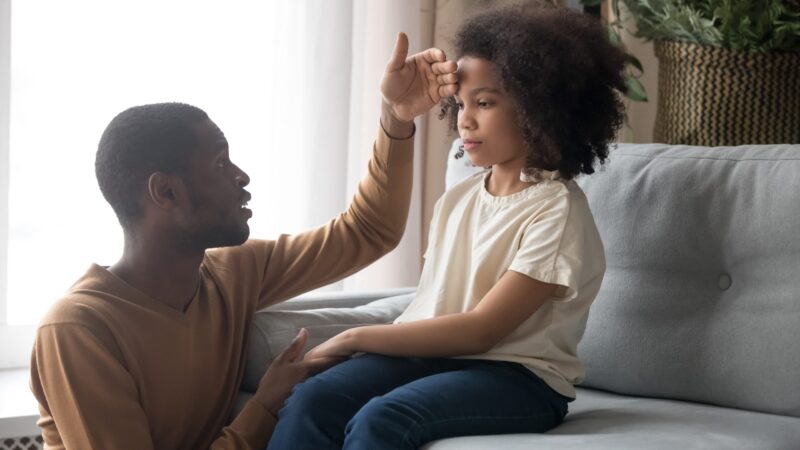 A father checking daughters temperature with back of hand