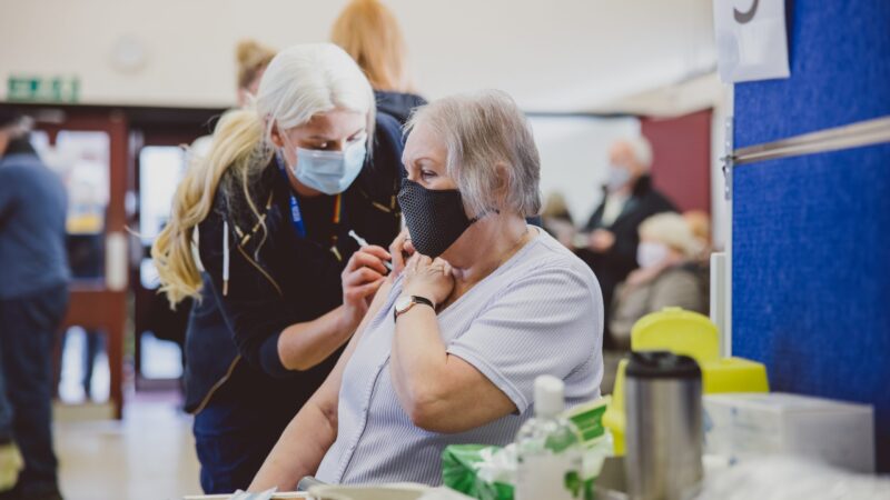 A female patient getting a vaccination from a female healthcare professional