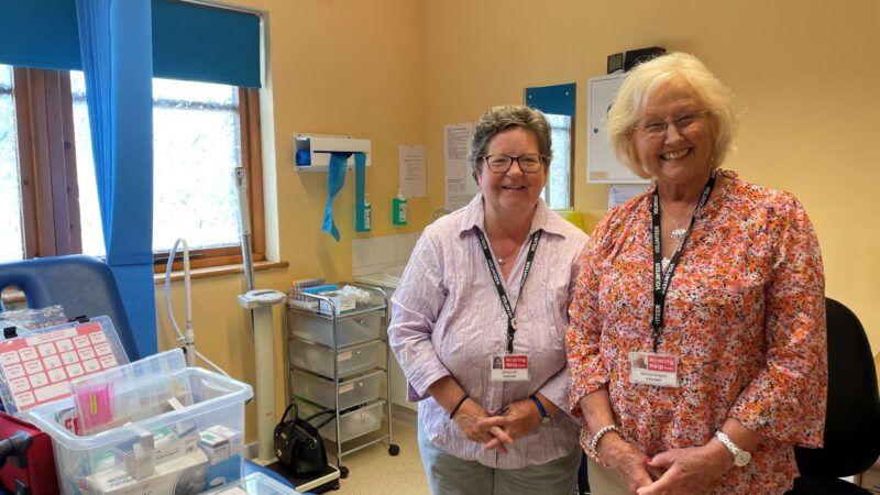 Two female Help for Hearing staff standing in a clinical room