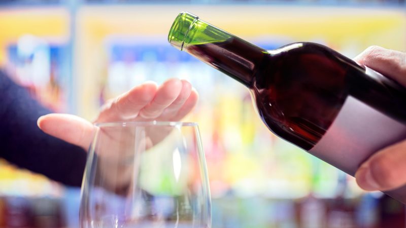 Woman refusing more alcohol from wine bottle